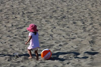 Rear view of boy playing on sand at beach