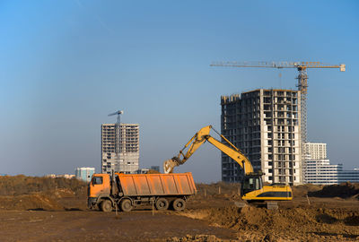 Cranes at construction site against sky