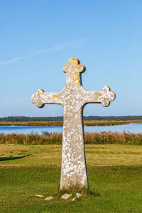 Cross on field against sky