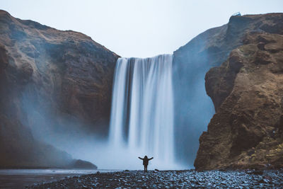 Woman standing against waterfall