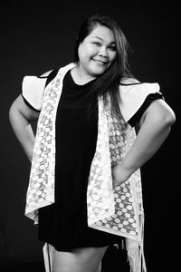 Portrait of smiling woman standing against black background