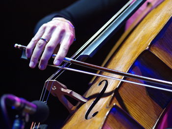 Hand playing cello strings at classical concert