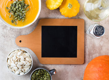 A chalk blank text board surrounded by pumpkin cream soup, pumpkin and seeds. top view. recipe. 