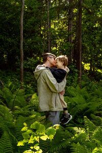 Father embracing with son while standing in forest
