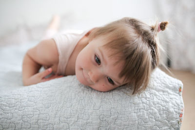 Funny girl toddler with a smile lying on the bed, close-up, concept happy happy childhood,