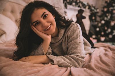 Portrait of a smiling young woman lying on bed