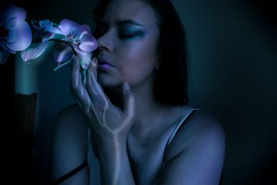 Close-up of woman smelling flower in darkroom