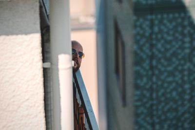 Man wearing sunglasses by wall