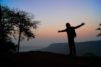 Silhouette man standing on mountain against clear sky