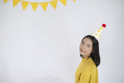 Portrait of a smiling young woman standing against wall