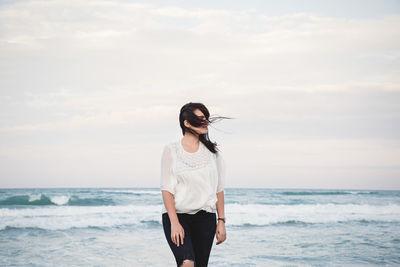 Young woman at seaside with hair in the air