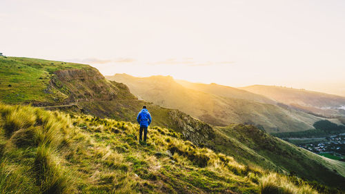 Rear view of man standing on mountain against sky