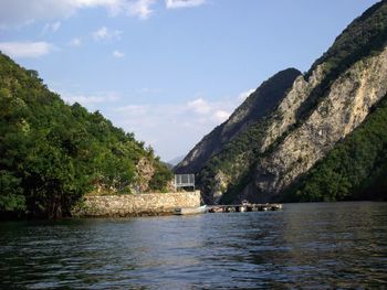 Scenic view of river by tree mountains against sky