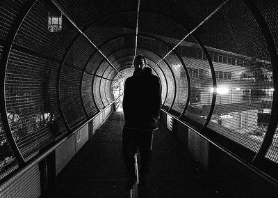 Rear view of silhouette man standing on illuminated ceiling