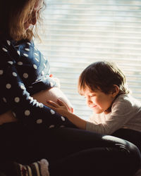 Son looking at pregnant mother belly