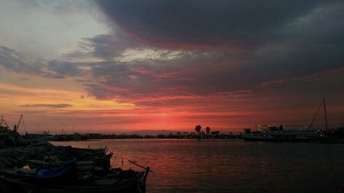 Boats moored in sea against sky during sunset