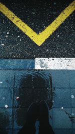 Low section of person standing on wet road