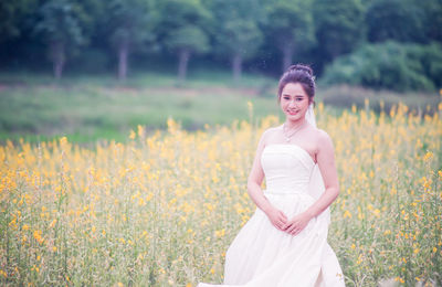 Portrait of smiling bride standing on field