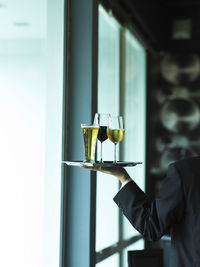 Midsection of waiter holding drinks in tray at restaurant