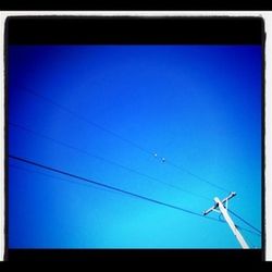 Low angle view of power lines against blue sky