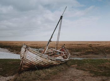 Abandoned boat on shore against sky