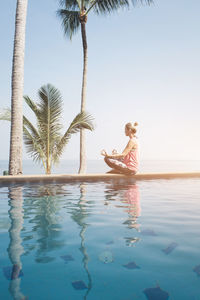 Woman swimming in pool against sea