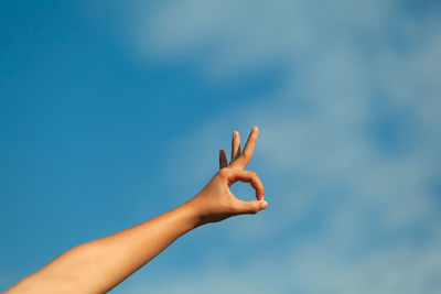 Cropped hand of woman gesturing against sky