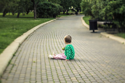 Rear view of girl sitting in park