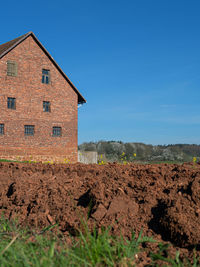 House on field against clear blue sky