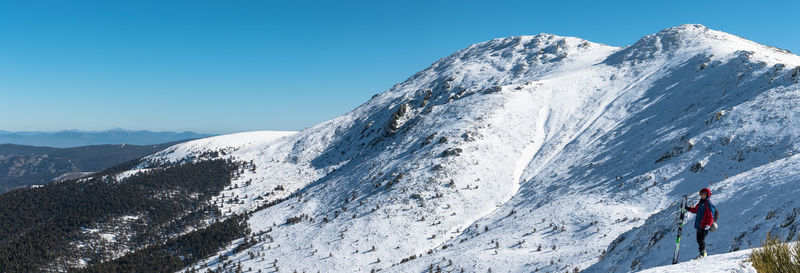 Person standing on snowcapped mountains against clear sky