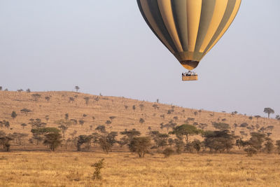 Hot air balloons on field against clear sky