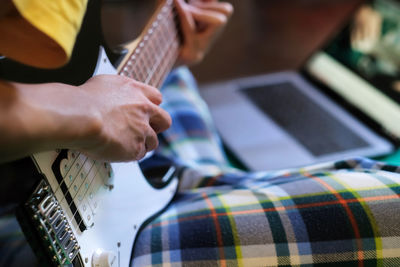 Midsection of man playing guitar