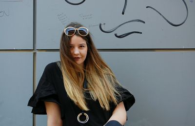 Beautiful young woman standing against wall