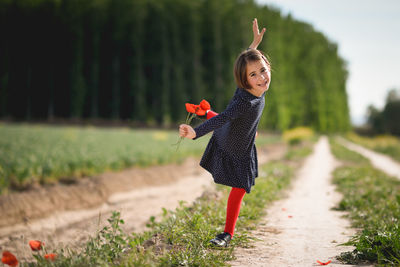 Portrait of smiling girl with flowers posing on field