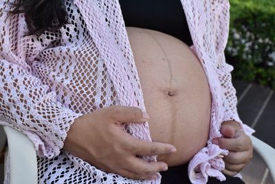 Midsection of woman sitting on purple outdoors