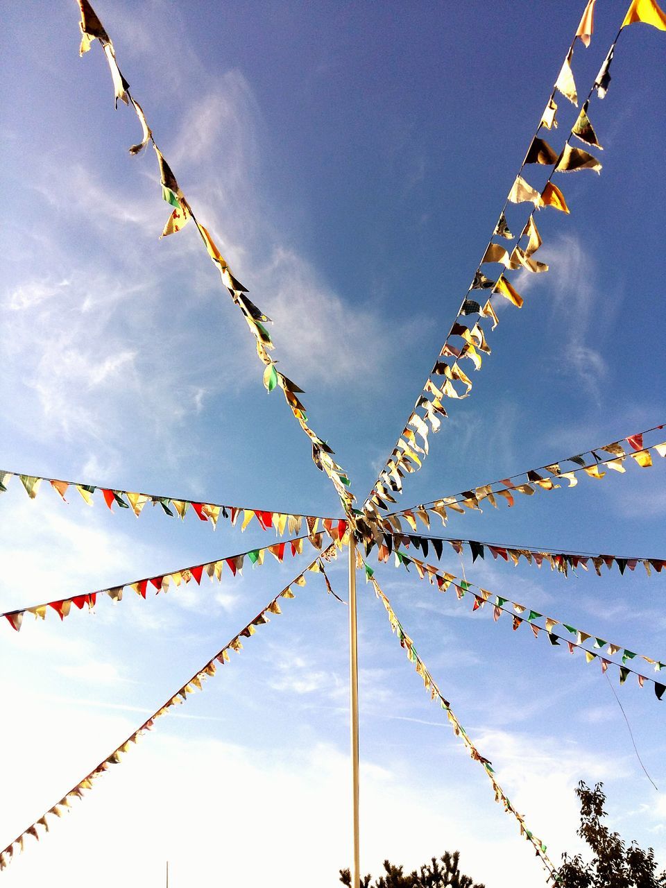 low angle view, sky, cloud - sky, bunting, celebration, outdoors, cultures, day, no people, cable, tradition, multi colored, hanging, spirituality, blue, nature