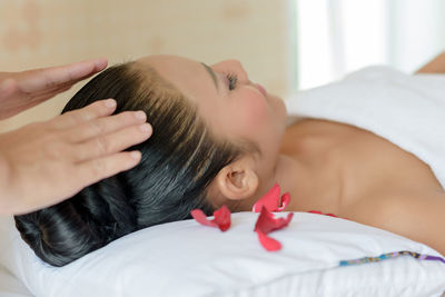 Therapist massaging while woman sleeping on bed at spa