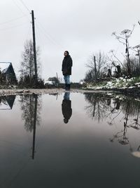 Man standing by lake against sky