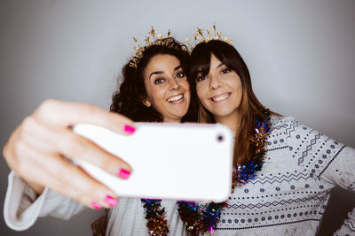 Portrait of smiling women doing selfie against gray backgrounds