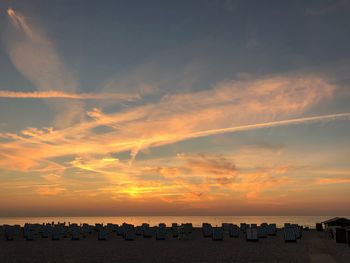 Silhouette people on beach against sky during sunset