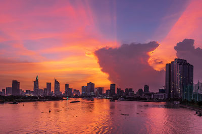 Scenic view of river amidst buildings against sky during sunset