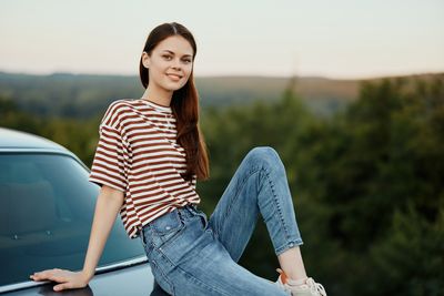 Portrait of young woman standing against sky