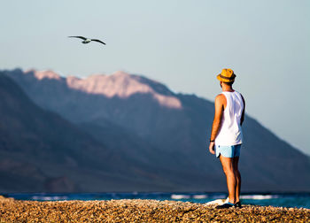 Rear view of man standing on mountain against sky