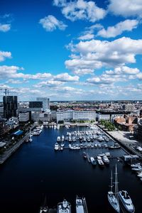 High angle view of boats moored at harbor against buildings in city