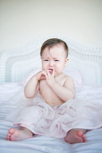 Full length portrait of cute baby girl crying on bed