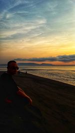 Man looking at sea against sky during sunset