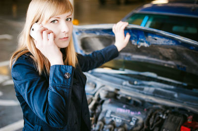 Portrait of woman talking on mobile phone by car