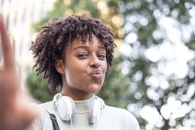  young model with afro hair with a positive attitude. afro woman with headphones takes a selfie