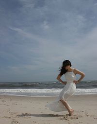 Woman posing at beach against sky