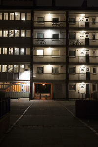 Illuminated street amidst buildings in city at night